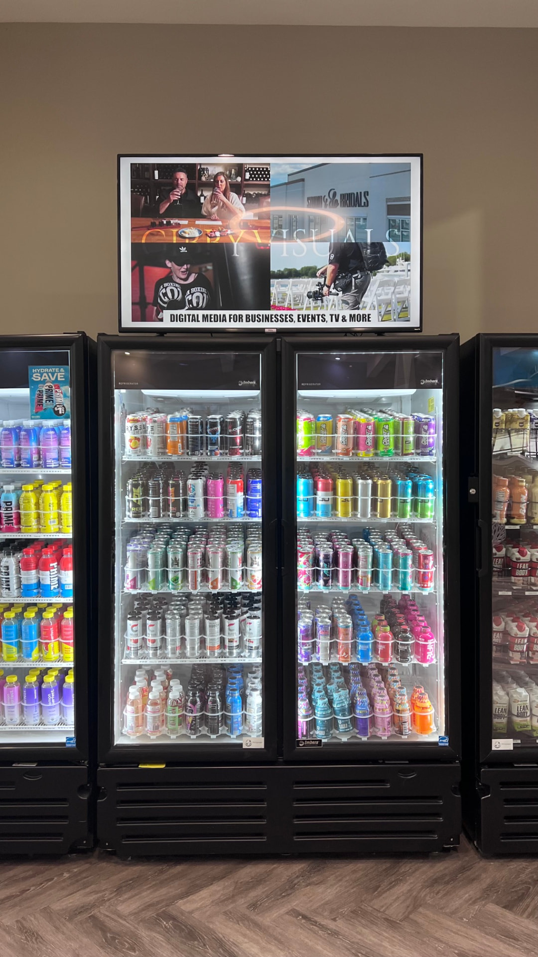 Digital advertising screen displaying branded content above beverage coolers in a Virginia venue